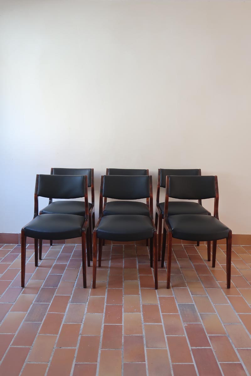 Lot de six chaises scandinaves vintage en teck massif avec assise et dossier en skaï noir, style Niels Otto Møller ou Erik Buch, présentées seules et en mise en situation dans différents espaces.