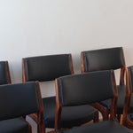 Lot de six chaises scandinaves vintage en teck massif avec assise et dossier en skaï noir, style Niels Otto Møller ou Erik Buch, présentées seules et en mise en situation dans différents espaces.