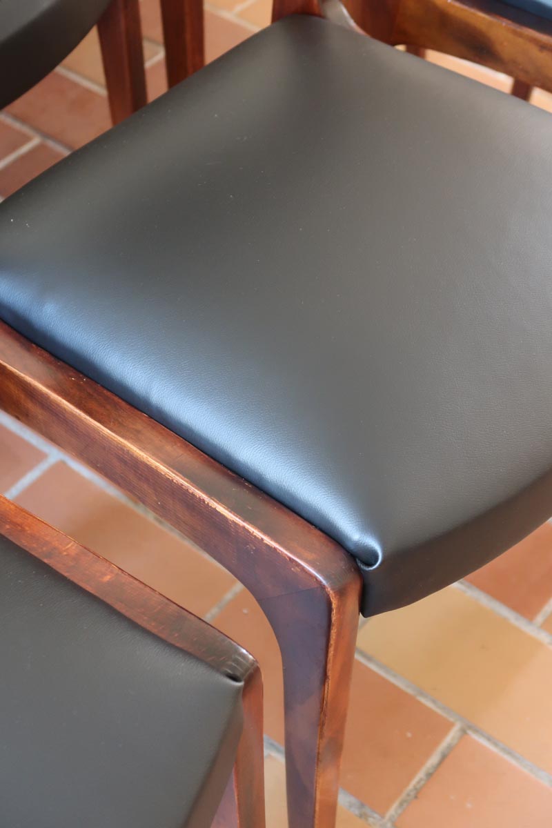 Lot de six chaises scandinaves vintage en teck massif avec assise et dossier en skaï noir, style Niels Otto Møller ou Erik Buch, présentées seules et en mise en situation dans différents espaces.