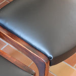 Lot de six chaises scandinaves vintage en teck massif avec assise et dossier en skaï noir, style Niels Otto Møller ou Erik Buch, présentées seules et en mise en situation dans différents espaces.