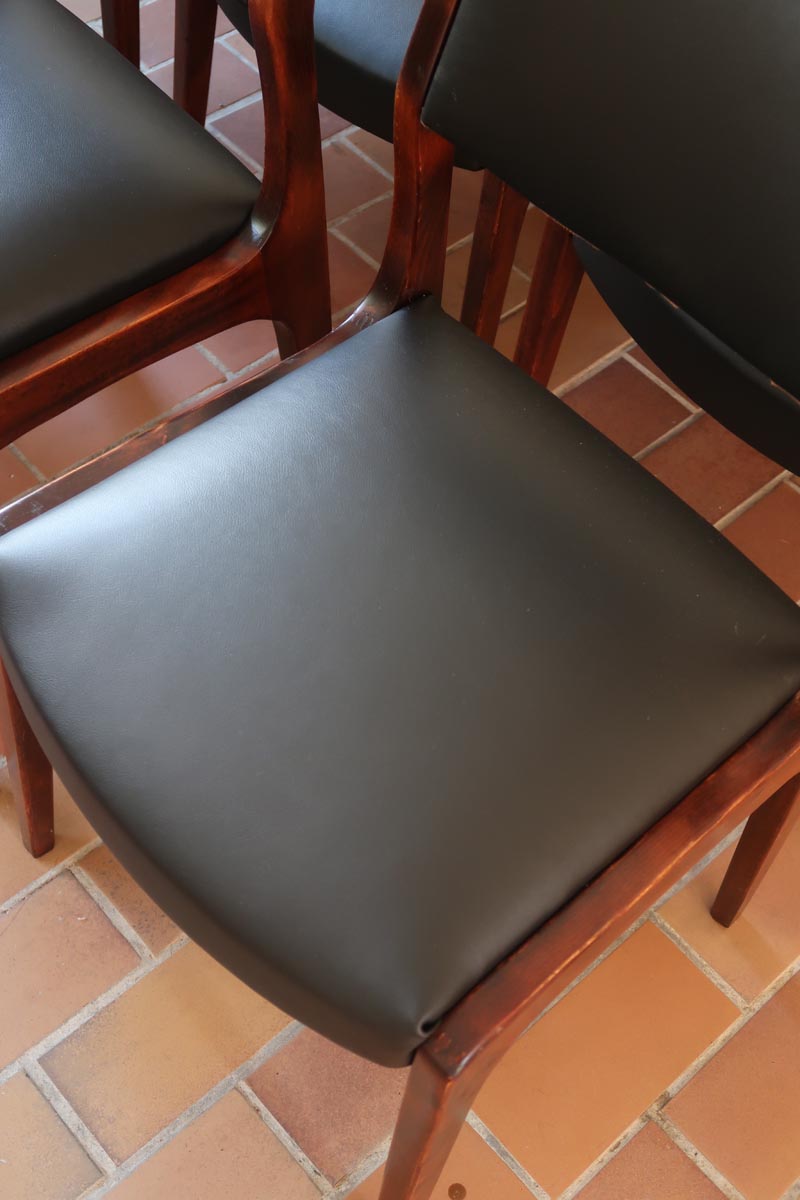 Lot de six chaises scandinaves vintage en teck massif avec assise et dossier en skaï noir, style Niels Otto Møller ou Erik Buch, présentées seules et en mise en situation dans différents espaces.