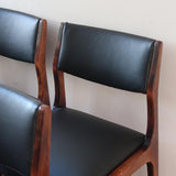 Lot de six chaises scandinaves vintage en teck massif avec assise et dossier en skaï noir, style Niels Otto Møller ou Erik Buch, présentées seules et en mise en situation dans différents espaces.