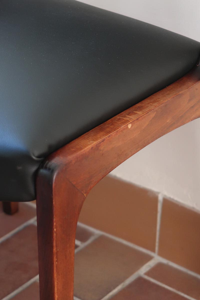 Lot de six chaises scandinaves vintage en teck massif avec assise et dossier en skaï noir, style Niels Otto Møller ou Erik Buch, présentées seules et en mise en situation dans différents espaces.