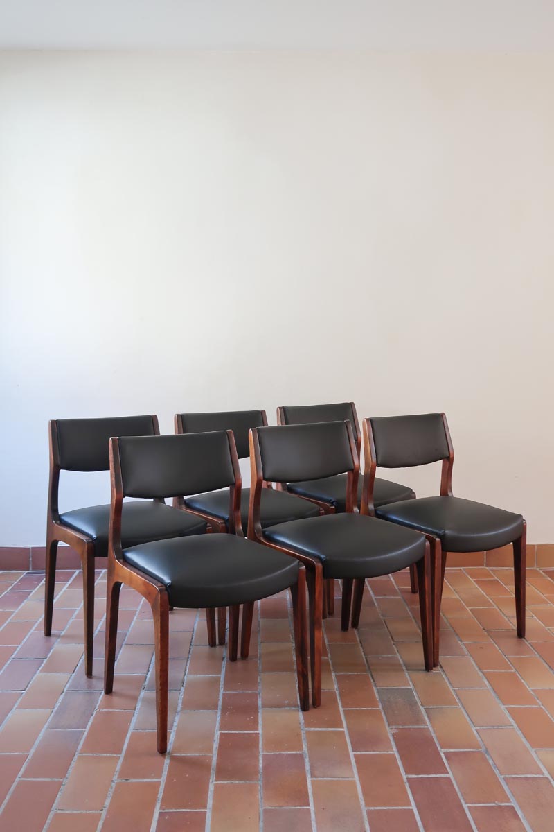 Lot de six chaises scandinaves vintage en teck massif avec assise et dossier en skaï noir, style Niels Otto Møller ou Erik Buch, présentées seules et en mise en situation dans différents espaces.