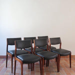 Lot de six chaises scandinaves vintage en teck massif avec assise et dossier en skaï noir, style Niels Otto Møller ou Erik Buch, présentées seules et en mise en situation dans différents espaces.