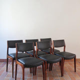 Lot de six chaises scandinaves vintage en teck massif avec assise et dossier en skaï noir, style Niels Otto Møller ou Erik Buch, présentées seules et en mise en situation dans différents espaces.
