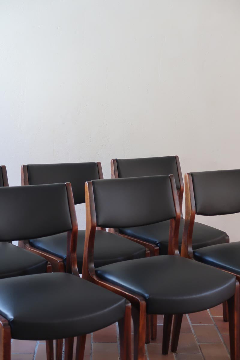 Lot de six chaises scandinaves vintage en teck massif avec assise et dossier en skaï noir, style Niels Otto Møller ou Erik Buch, présentées seules et en mise en situation dans différents espaces.