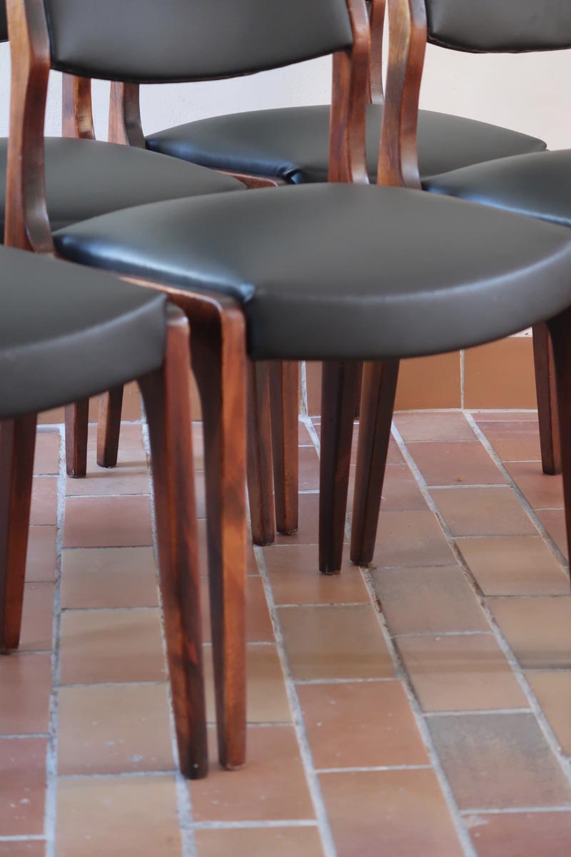 Lot de six chaises scandinaves vintage en teck massif avec assise et dossier en skaï noir, style Niels Otto Møller ou Erik Buch, présentées seules et en mise en situation dans différents espaces.