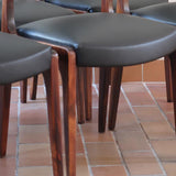 Lot de six chaises scandinaves vintage en teck massif avec assise et dossier en skaï noir, style Niels Otto Møller ou Erik Buch, présentées seules et en mise en situation dans différents espaces.