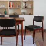 Lot de six chaises scandinaves vintage en teck massif avec assise et dossier en skaï noir, style Niels Otto Møller ou Erik Buch, présentées seules et en mise en situation dans différents espaces.