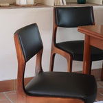 Lot de six chaises scandinaves vintage en teck massif avec assise et dossier en skaï noir, style Niels Otto Møller ou Erik Buch, présentées seules et en mise en situation dans différents espaces.