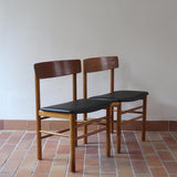 Paire de chaises scandinaves en bois et skaï noir — années 60