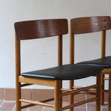 Paire de chaises scandinaves en bois et skaï noir — années 60