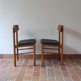 Paire de chaises scandinaves en bois et skaï noir — années 60