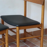 Paire de chaises scandinaves en bois et skaï noir — années 60