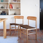 Paire de chaises scandinaves en bois clair avec assises en cuir brun, design des années 1960.