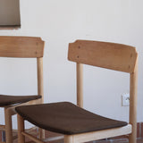 Paire de chaises scandinaves en bois clair avec assises en cuir brun, design des années 1960.