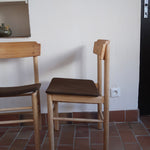 Paire de chaises scandinaves en bois clair avec assises en cuir brun, design des années 1960.