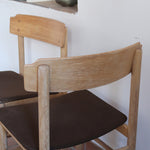 Paire de chaises scandinaves en bois clair avec assises en cuir brun, design des années 1960.