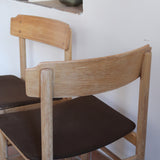 Paire de chaises scandinaves en bois clair avec assises en cuir brun, design des années 1960.