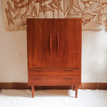 Armoire vintage en bois des années 60 avec deux portes, deux tiroirs, poignées sculptées et pieds compas.