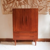 Armoire vintage en bois des années 60 avec deux portes, deux tiroirs, poignées sculptées et pieds compas.