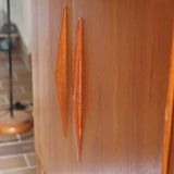 Armoire vintage en bois des années 60 avec deux portes, deux tiroirs, poignées sculptées et pieds compas.