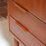 Armoire vintage en bois des années 60 avec deux portes, deux tiroirs, poignées sculptées et pieds compas.