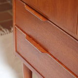 Armoire vintage en bois des années 60 avec deux portes, deux tiroirs, poignées sculptées et pieds compas.
