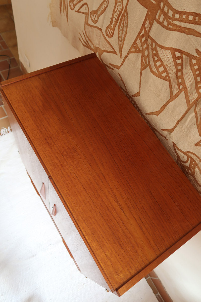 Armoire vintage en bois des années 60 avec deux portes, deux tiroirs, poignées sculptées et pieds compas.