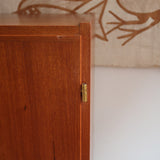 Armoire vintage en bois des années 60 avec deux portes, deux tiroirs, poignées sculptées et pieds compas.