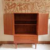 Armoire vintage en bois des années 60 avec deux portes, deux tiroirs, poignées sculptées et pieds compas.