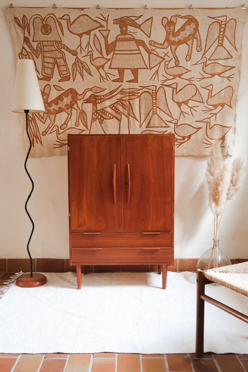 Armoire vintage en bois des années 60 avec deux portes, deux tiroirs, poignées sculptées et pieds compas.