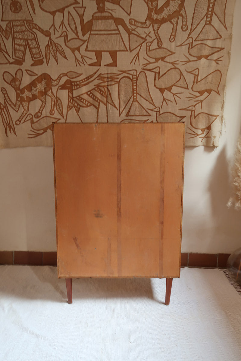Armoire vintage en bois des années 60 avec deux portes, deux tiroirs, poignées sculptées et pieds compas.