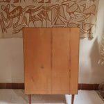 Armoire vintage en bois des années 60 avec deux portes, deux tiroirs, poignées sculptées et pieds compas.
