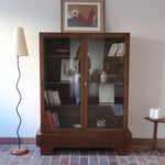 Bibliothèque vitrée vintage en bois de noyer, années 60, esprit Art déco, deux portes vitrées à encadrement de bois fermant à clé, quatre tablettes réglables, socle débordant à gradins sur deux patins pleins