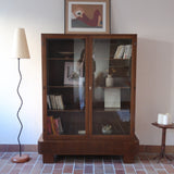 Bibliothèque vitrée vintage en bois de noyer, années 60, esprit Art déco, deux portes vitrées à encadrement de bois fermant à clé, quatre tablettes réglables, socle débordant à gradins sur deux patins pleins