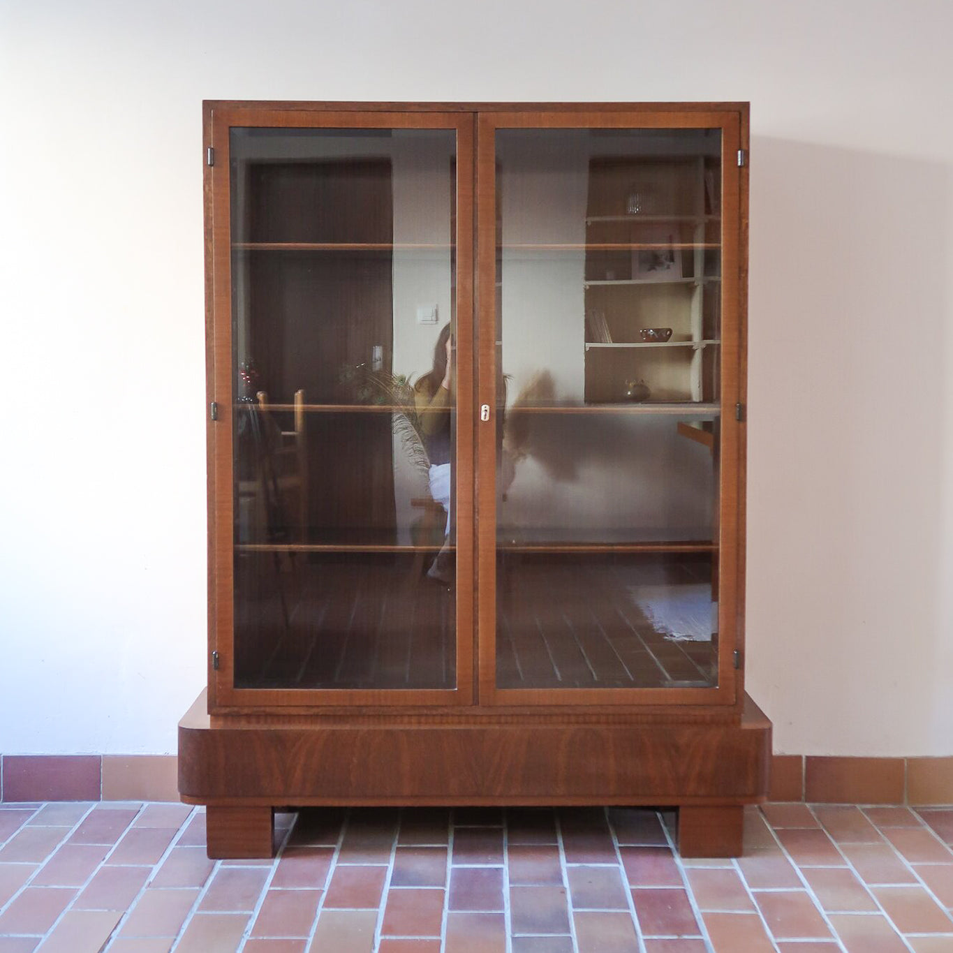 Bibliothèque vitrée vintage en bois de noyer, années 60, esprit Art déco, deux portes vitrées à encadrement de bois fermant à clé, quatre tablettes réglables, socle débordant à gradins sur deux patins pleins