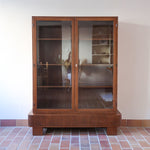 Bibliothèque vitrée vintage en bois de noyer, années 60, esprit Art déco, deux portes vitrées à encadrement de bois fermant à clé, quatre tablettes réglables, socle débordant à gradins sur deux patins pleins