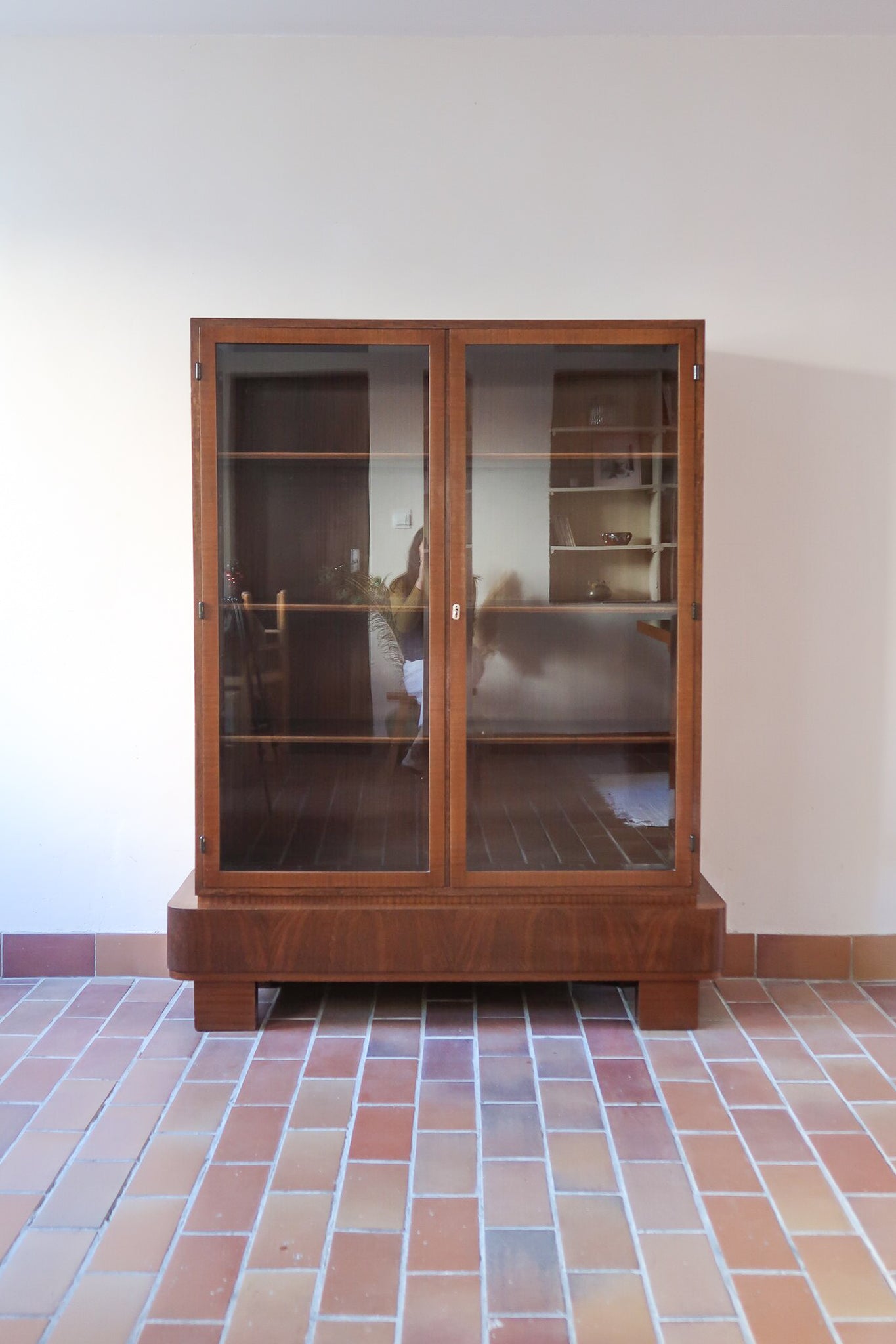 Bibliothèque vitrée vintage en bois de noyer, années 60, esprit Art déco, deux portes vitrées à encadrement de bois fermant à clé, quatre tablettes réglables, socle débordant à gradins sur deux patins pleins