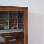 Bibliothèque vitrée vintage en bois de noyer, années 60, esprit Art déco, deux portes vitrées à encadrement de bois fermant à clé, quatre tablettes réglables, socle débordant à gradins sur deux patins pleins
