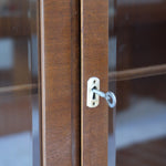 Bibliothèque vitrée vintage en bois de noyer, années 60, esprit Art déco, deux portes vitrées à encadrement de bois fermant à clé, quatre tablettes réglables, socle débordant à gradins sur deux patins pleins