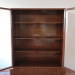 Bibliothèque vitrée vintage en bois de noyer, années 60, esprit Art déco, deux portes vitrées à encadrement de bois fermant à clé, quatre tablettes réglables, socle débordant à gradins sur deux patins pleins