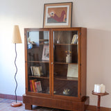 Bibliothèque vitrée vintage en bois de noyer, années 60, esprit Art déco, deux portes vitrées à encadrement de bois fermant à clé, quatre tablettes réglables, socle débordant à gradins sur deux patins pleins