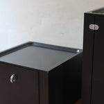Duo de caissons vintage Roche Bobois années 90, bois laqué noir, module haut à abattant et module cube à porte, poignées chromées encastrées, intérieur laqué blanc