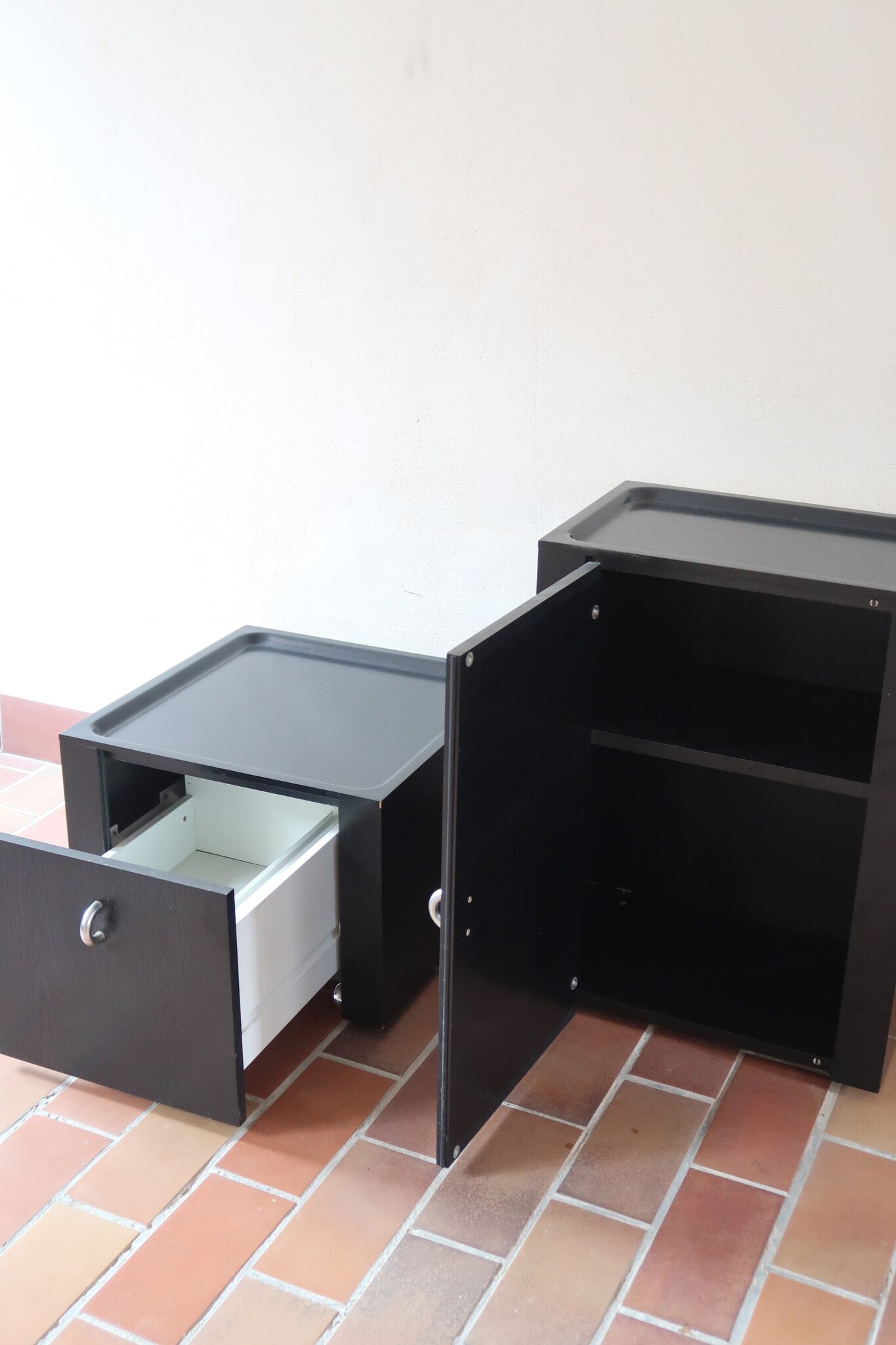 Duo de caissons vintage Roche Bobois années 90, bois laqué noir, module haut à abattant et module cube à porte, poignées chromées encastrées, intérieur laqué blanc