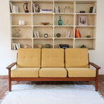 Canapé 3 places scandinave en teck des années 60 avec coussins en tissu jaune moutarde et structure type banquette.
