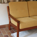Canapé 3 places scandinave en teck des années 60 avec coussins en tissu jaune moutarde et structure type banquette.
