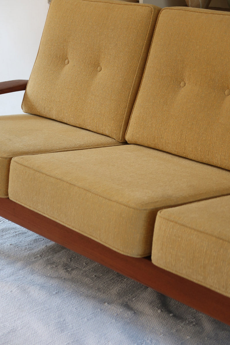 Canapé 3 places scandinave en teck des années 60 avec coussins en tissu jaune moutarde et structure type banquette.