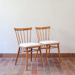 Paire de chaises vintage en hêtre massif des années 60 avec assise en tissu bouclette clair, design Antonín Šuman pour Tatra Nabytok, présentées seules et en mise en situation.